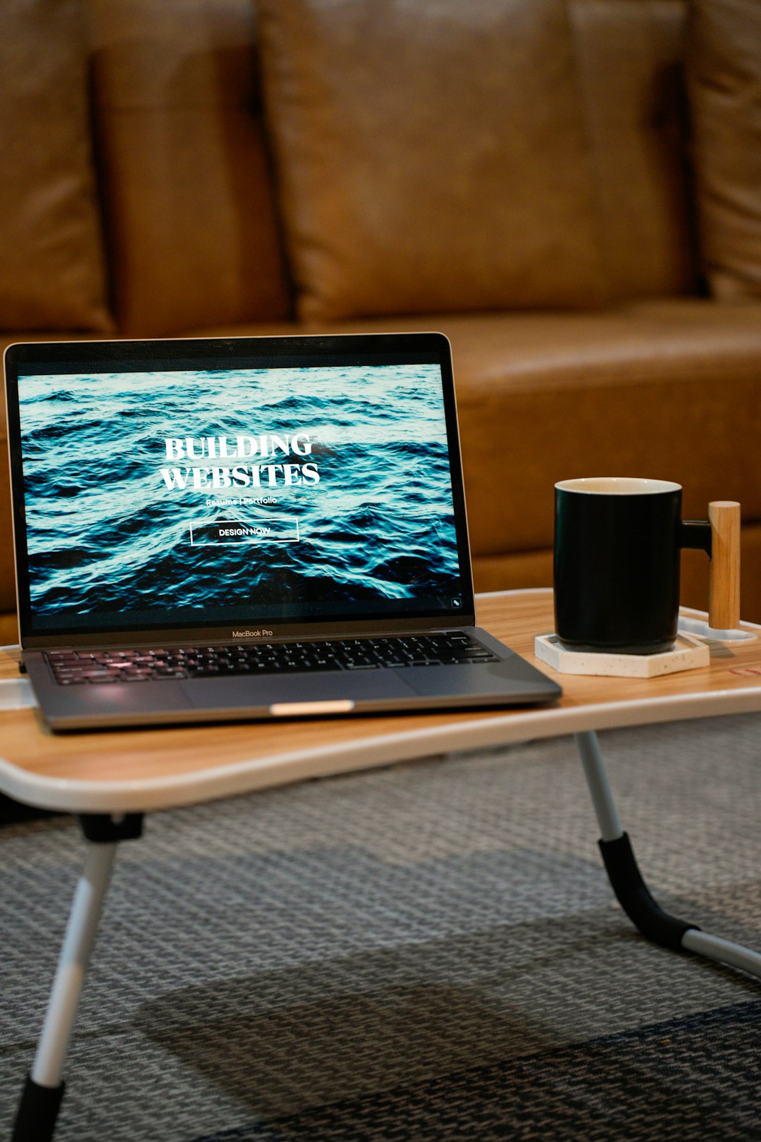 Services Build websites for your portfolio, resume, internal communications, wedding invitations, and more! A laptop, MacBook, on top of a portable table with coffee tea mug on the side.