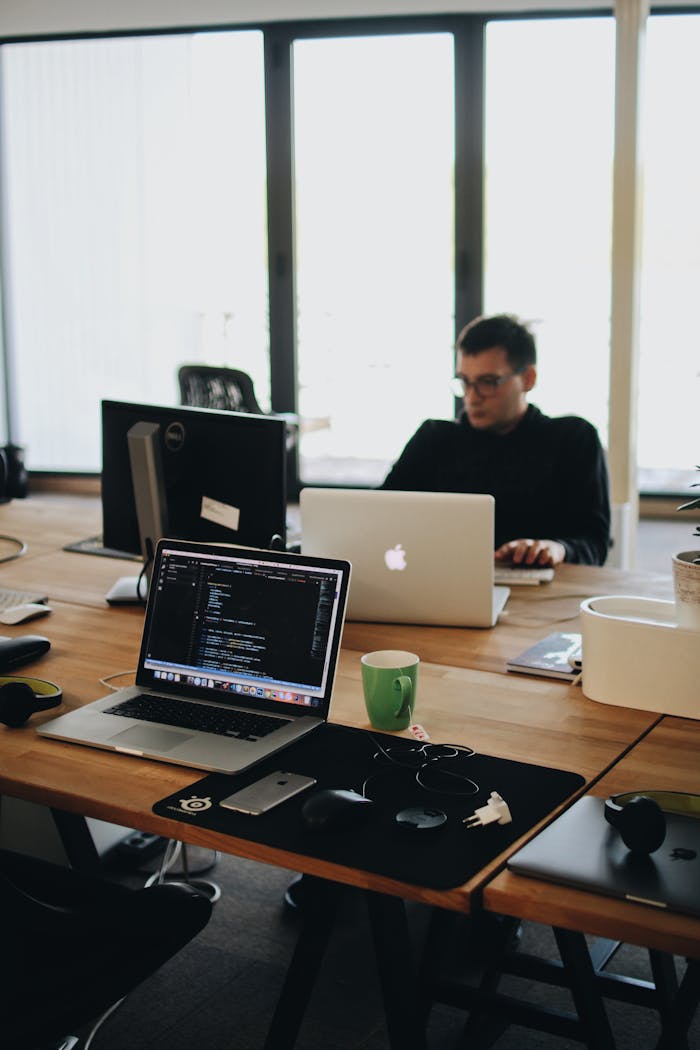 Home A web developer working on code in a modern office setting with multiple devices.
